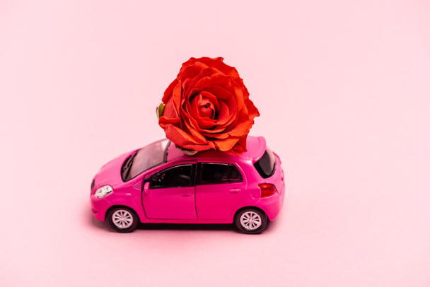 toy car and red rose on pink background - Foto, Bild