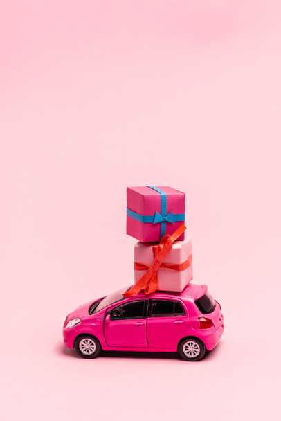 giocattolo auto e scatole regalo su sfondo rosa - Foto, immagini