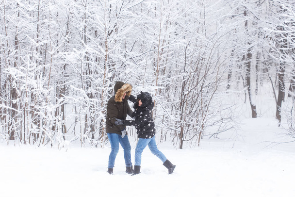 Életmód, szezon és szabadidő koncepció - Vicces pár hógolyózik a téli parkban - Fotó, kép