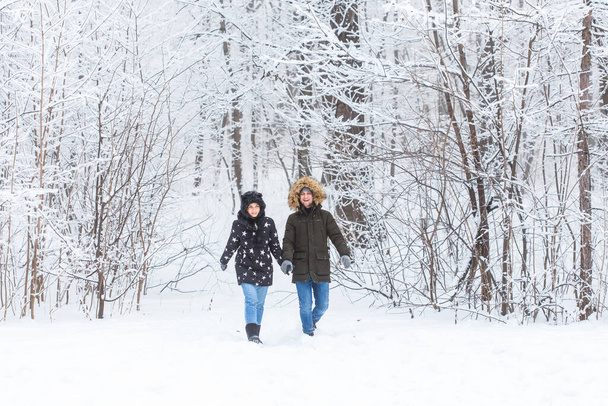 Young couple in love walks in the snowy forest. Active winter holidays. - Foto, afbeelding