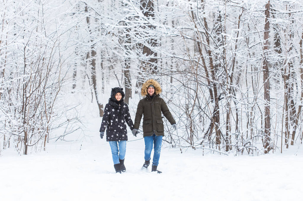 Mladý pár procházející se v zasněženém parku. Zimní sezóna. - Fotografie, Obrázek