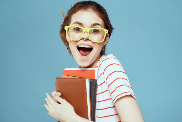 Schöne Studentin mit Notizblock und gelber Brille auf blauem Hintergrund - Foto, Bild