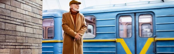 idős férfi őszi ruhák áll metró platform vonattal a háttérben, banner - Fotó, kép