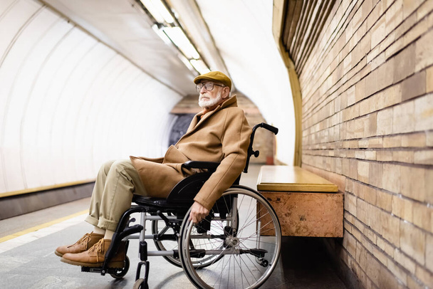 w wieku niepełnosprawny mężczyzna jesienią ubrania siedzi na wózku inwalidzkim na podziemnej platformie - Zdjęcie, obraz