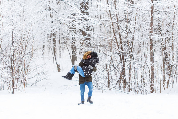 A fiatal szerelmesek jól érzik magukat a havas erdőben. Aktív téli szünetek. - Fotó, kép