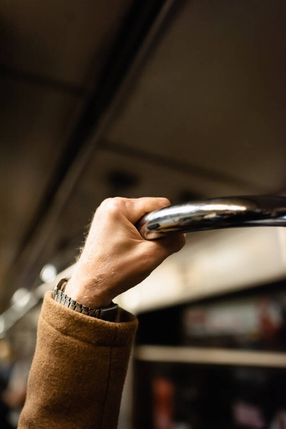 cropped view of aged man holding handrail in wagon of underground train - Φωτογραφία, εικόνα