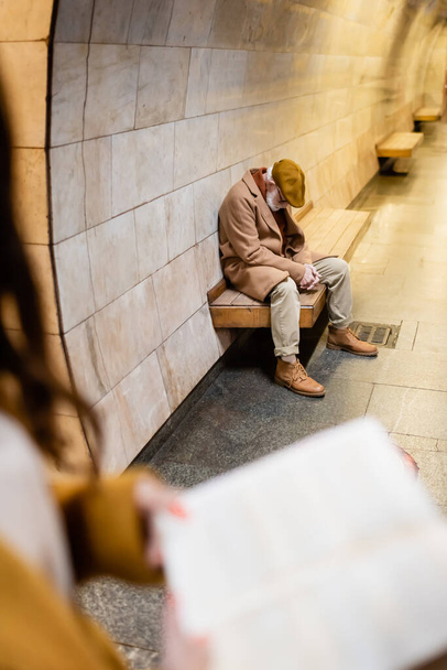 senior en tenue d'automne dormant sur banc plate-forme de métro au premier plan flou - Photo, image