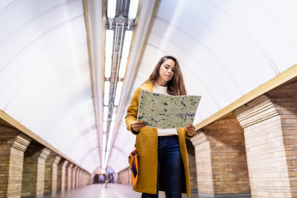 fiatal elegáns nő őszi ruhákban nézi város térképe metró állomás - Fotó, kép