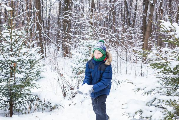 Tatlı çocuk karla oynuyor, eğleniyor, gülümsüyor. Kış parkında ergen. Aktif yaşam tarzı, kış aktivitesi, açık hava kış oyunları, kartopu. - Fotoğraf, Görsel