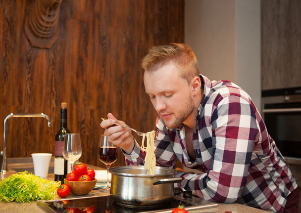 Handsome man cooking at home preparing pasta - Photo, Image