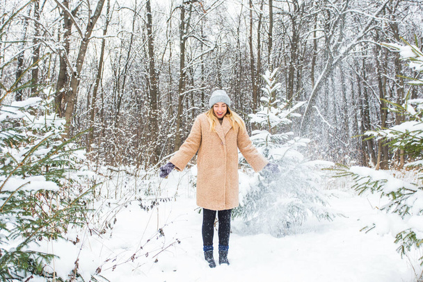 Молода жінка кидає сніг в повітрі в сонячний зимовий день, вона щаслива і весела
. - Фото, зображення