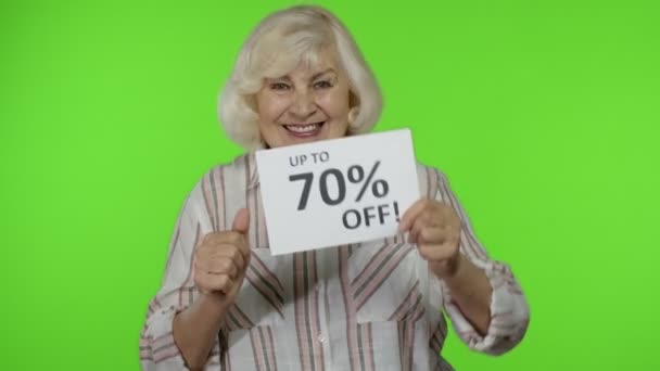 Seniorin zeigt bis zu 70 Prozent Rabatt-Schild und jubelt Chroma-Schlüssel - Filmmaterial, Video
