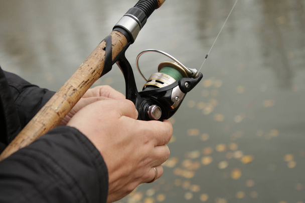 The man is fishing with a line. Hands holding a fishing rod close up - Фото, изображение