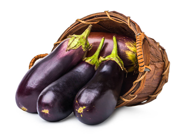 Rijpe aubergines in rieten mand geïsoleerd op wit - Foto, afbeelding