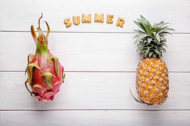 白い熱帯果実。白木の背景にドラゴンフルーツとパイナップル。健康食品。夏のコンセプト。トップビュー、コピースペース、フラットレイアウト. - 写真・画像