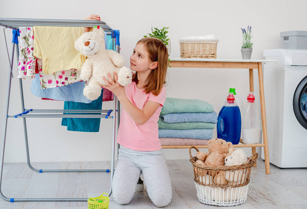 Little girl hanging teddy bear on dryer - Zdjęcie, obraz