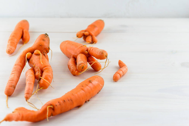 Ugly carrot on a wooden background. Ugly vegetables concept. Horizontal orientation, copy space. - Fotoğraf, Görsel