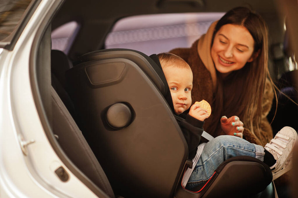 Young mother and child in car. Baby seat on chair. Safety driving concept. - Foto, immagini