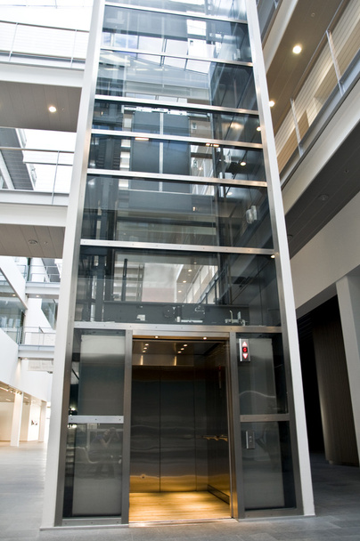 Big elevator made of glass and steel inside a business building - Photo, Image