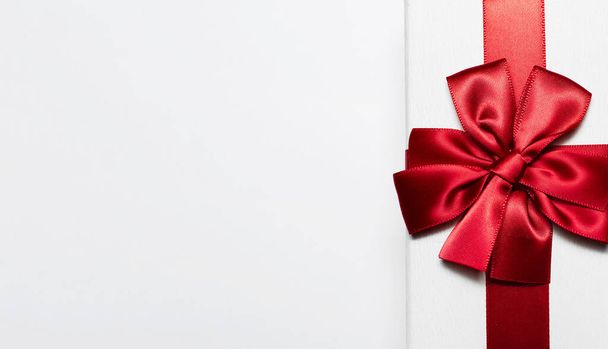 Close-up van witte geschenkdoos met rode strik geïsoleerd op witte achtergrond met kopieerruimte voor tekst. - Foto, afbeelding