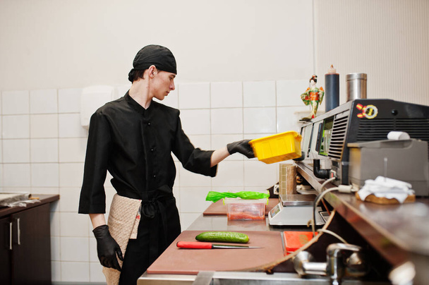 Professional chef wear in black making sushi and rolls in a restaurant kitchen of japanese traditional food.  - Fotoğraf, Görsel