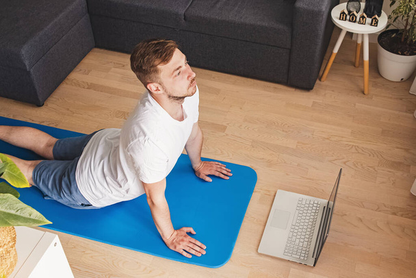 Young man doing yoga in his living room - Fotó, kép