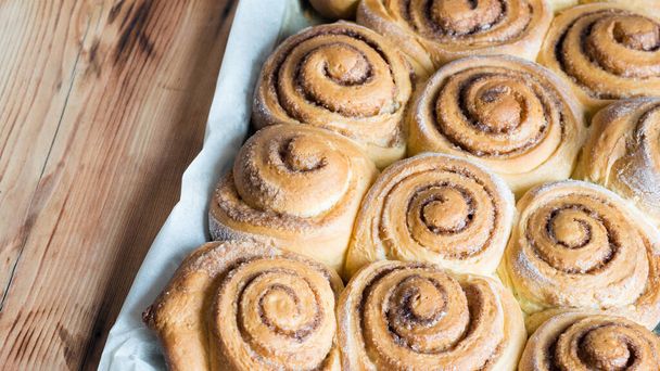 Freshly baked cinnamon buns cinnabons on parchment paper. Top view, close-up. Sweet Homemade Pastry christmas baking. - Foto, immagini