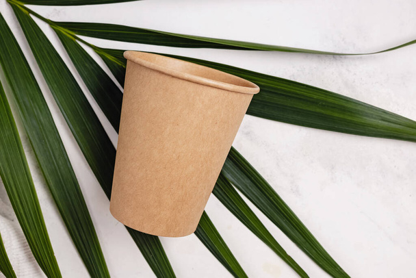 Coffee cup made of paper and green palm leaf - 写真・画像