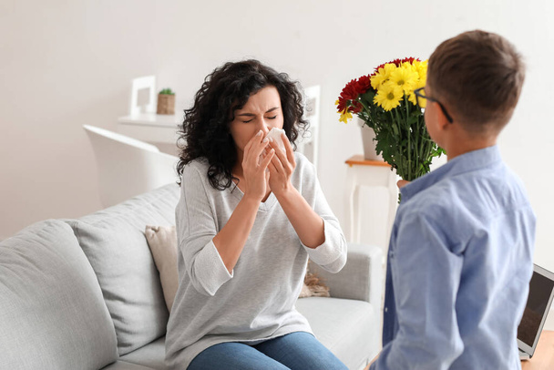 Little boy with flowers greeting his allergic mother at home - Photo, Image