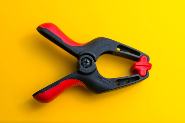 close-up photo of a clamp isolated on a yellow background - 写真・画像