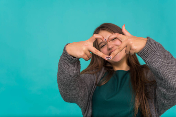 Portrait of cute teenage nice-looking cute lovely adorable sweet attractive cheerful cheery girl showing heart isolated over blue pastel background. showing heart gesture - Φωτογραφία, εικόνα