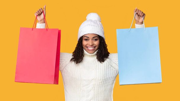 Mujer negra sosteniendo y mostrando dos bolsas de compras - Foto, imagen