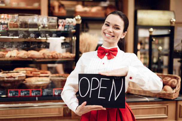 Young Woman with Open Sign Standing in Bakery. - Foto, immagini