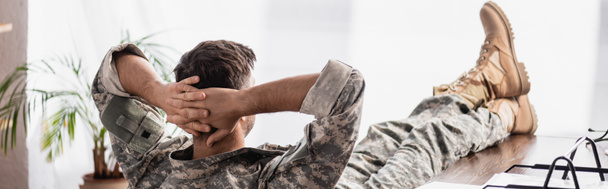 widok z tyłu żołnierz w mundurze wojskowym spoczywający w biurze, sztandar - Zdjęcie, obraz