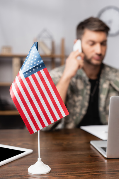 American flag and digital tablet near military man in uniform on blurred background - Foto, Imagen