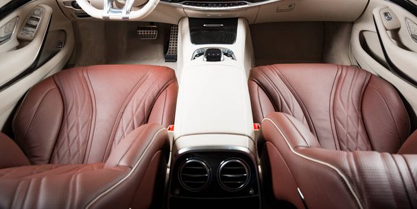 Nowoczesne luksusowe wnętrze samochodu - kierownica, dźwignia zmiany biegów i deska rozdzielcza. Luksusowe wnętrze samochodu. Beżowe wygodne siedzenia, kierownica, deska rozdzielcza, prędkościomierz, wyświetlacz. Skóra perforowana czerwono-biała. - Zdjęcie, obraz
