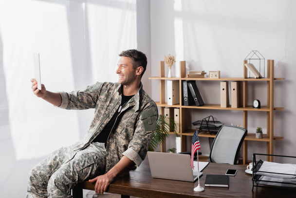onnellinen sotilas sotilasunivormussa digitaalisen tabletin avulla videokeskustelun aikana toimistossa - Valokuva, kuva