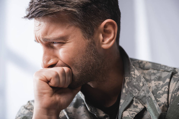 Askeri üniformalı bir adam ağlıyor ve ağzını sımsıkı kapatıyor. - Fotoğraf, Görsel