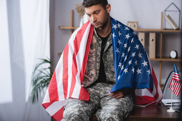 sad military man wrapped in american flag in office - Photo, Image