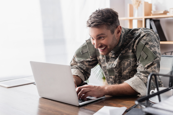 vzrušený voják psaní na klávesnici notebooku  - Fotografie, Obrázek