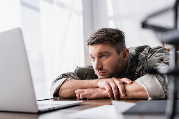 upset military man in uniform looking at laptop on table - Φωτογραφία, εικόνα