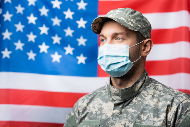 militaire en masque médical près du drapeau américain sur fond flou - Photo, image