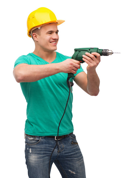 Smiling manual worker in helmet with drill machine - Fotó, kép