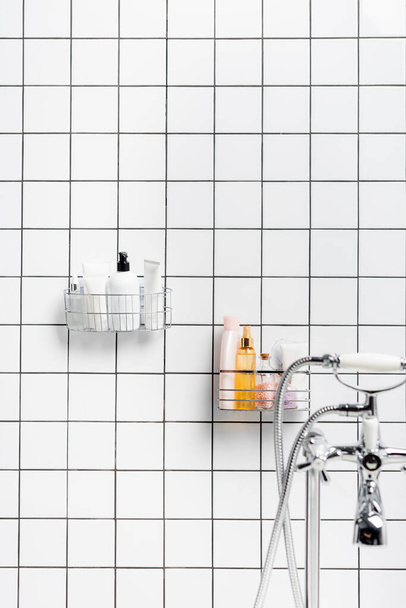 Toiletries near faucet on blurred foreground in modern white bathroom  - Zdjęcie, obraz