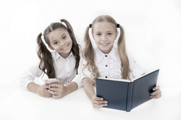 Getting information. Modern data storage instead big paper book. Little girls read paper book and ebook smartphone. Application for education. Educational application mobile phone. Education online - Фото, зображення