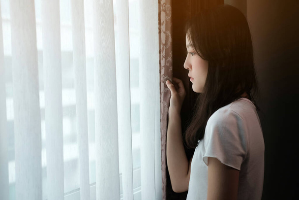 Eine depressive Asiatin steht am Fenster. - Foto, Bild