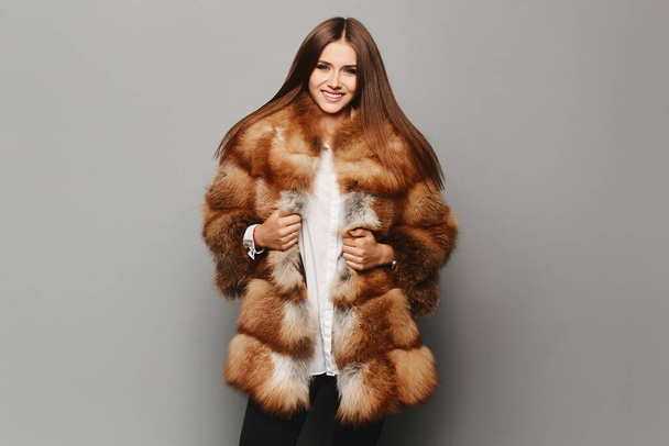Beautiful lady in a luxury elegant fur coat, isolated in the background. Model girl posing in eco-fur coat - Foto, immagini