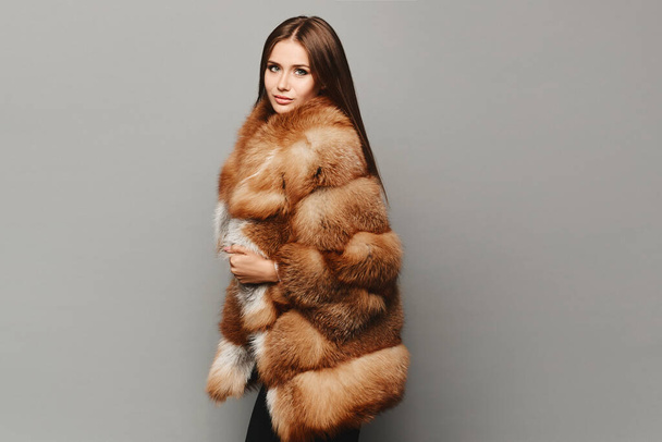 Jovem mulher em casaco de pele de luxo caro isolado no fundo cinza - Foto, Imagem