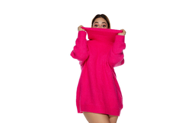Beautiful young woman in bright pink comfortable sweater, long sleeve isolated on white studio background - Foto, Imagen