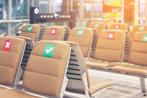 Αυτοκόλλητο σύμβολο σε καρέκλα στο διεθνές αεροδρόμιο. Νέες έννοιες της φυσιολογικής και κοινωνικής απόστασης, προστασία της νόσου του Coronavirus (Covid-19) λοίμωξη - Φωτογραφία, εικόνα